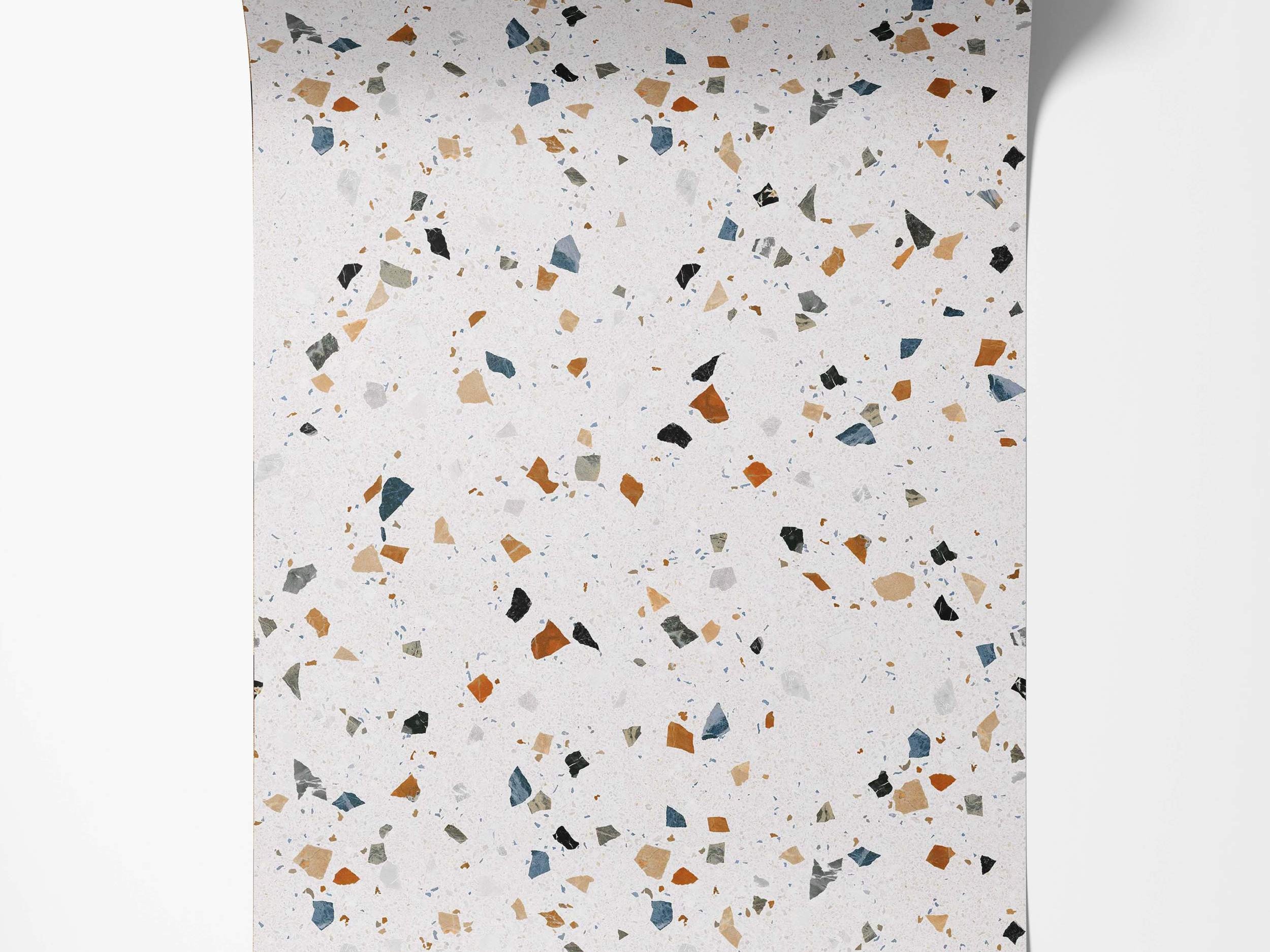 Wallpaper with a terrazzo pattern featuring blue, rust, beige, black, and gray chips on a light speckled background.