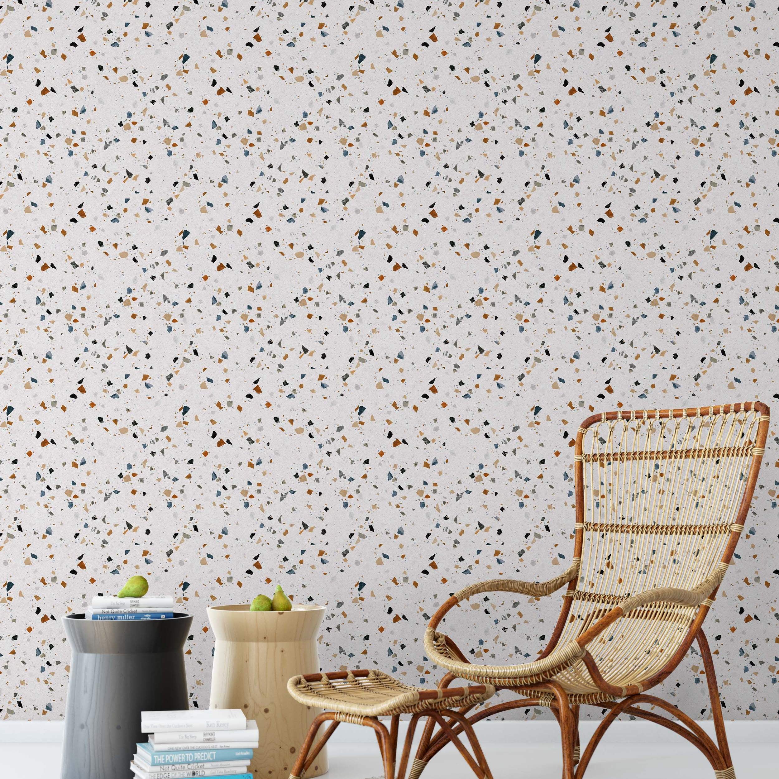 Terrazzo wallpaper featuring scattered, multi-colored chips in brown, blue, grey, and black on a light background.