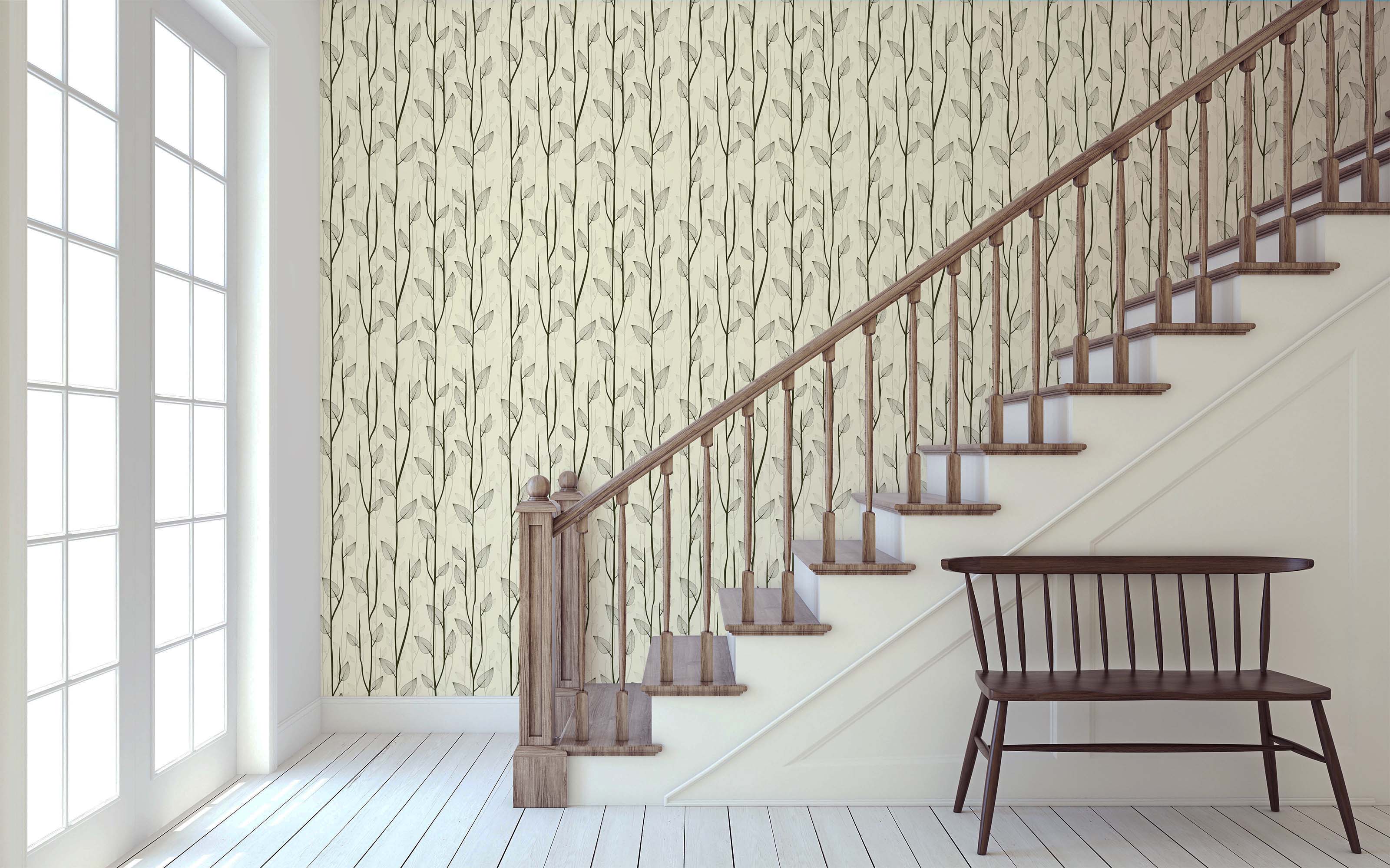 A wallpaper with a vertical pattern of delicate dark gray branches and translucent gray leaves on a cream background.