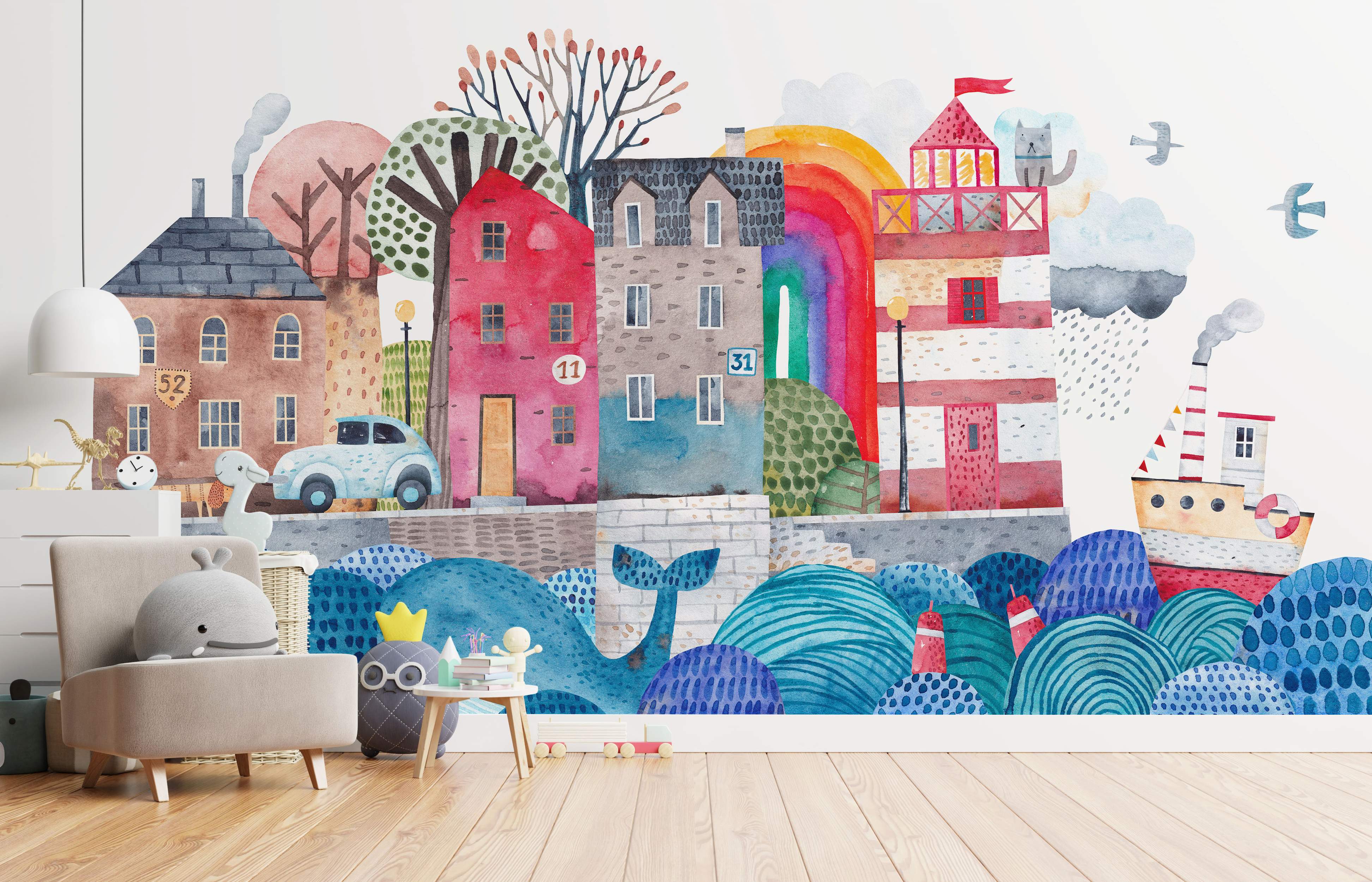 Watercolor mural depicting a whimsical coastal town scene with colorful houses, a lighthouse, a boat, a whale, and blue waves.