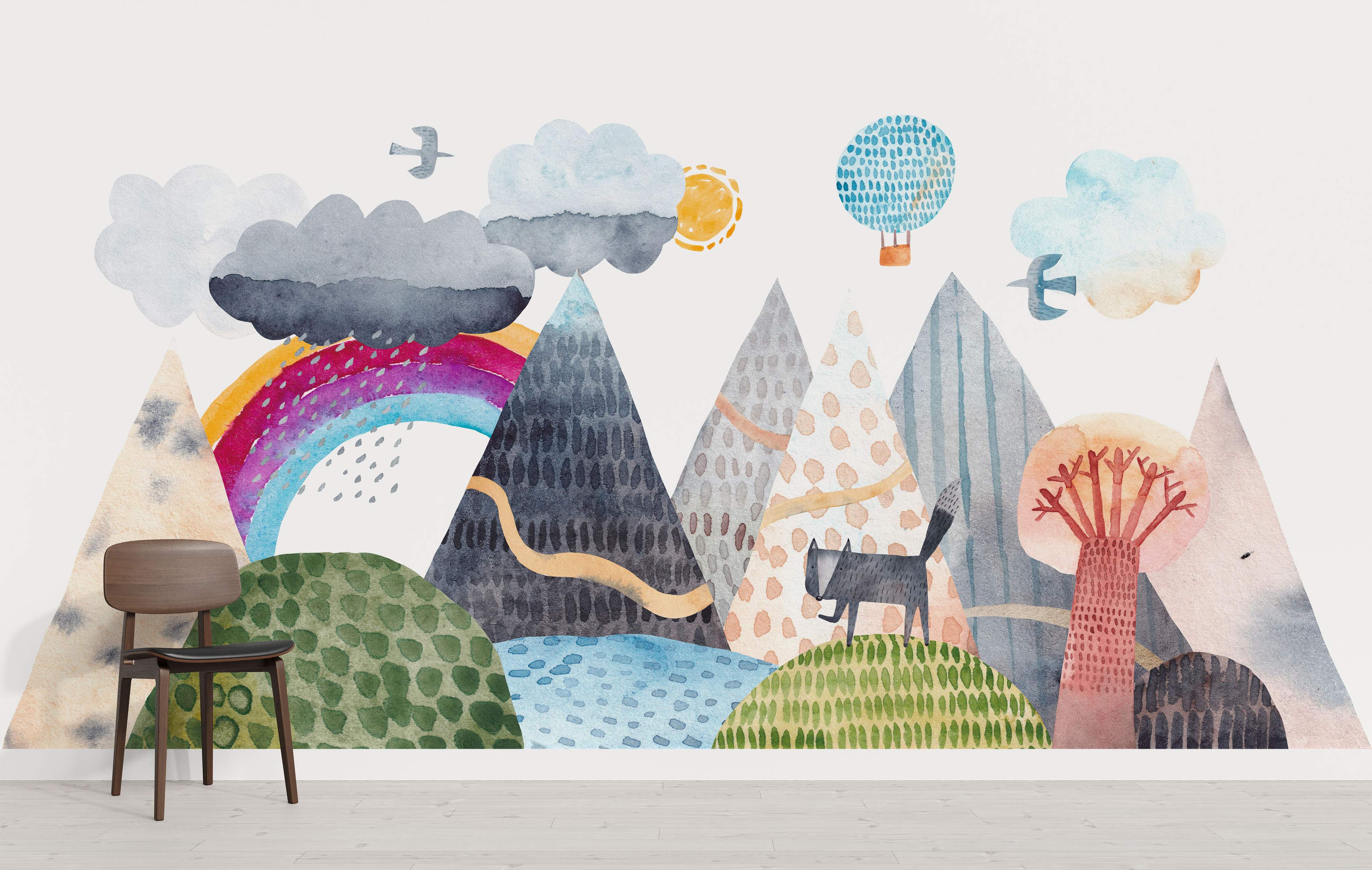 Whimsical watercolor landscape mural with patterned mountains, rolling hills, a rainbow, clouds, sun, birds, hot air balloon, and a cat.