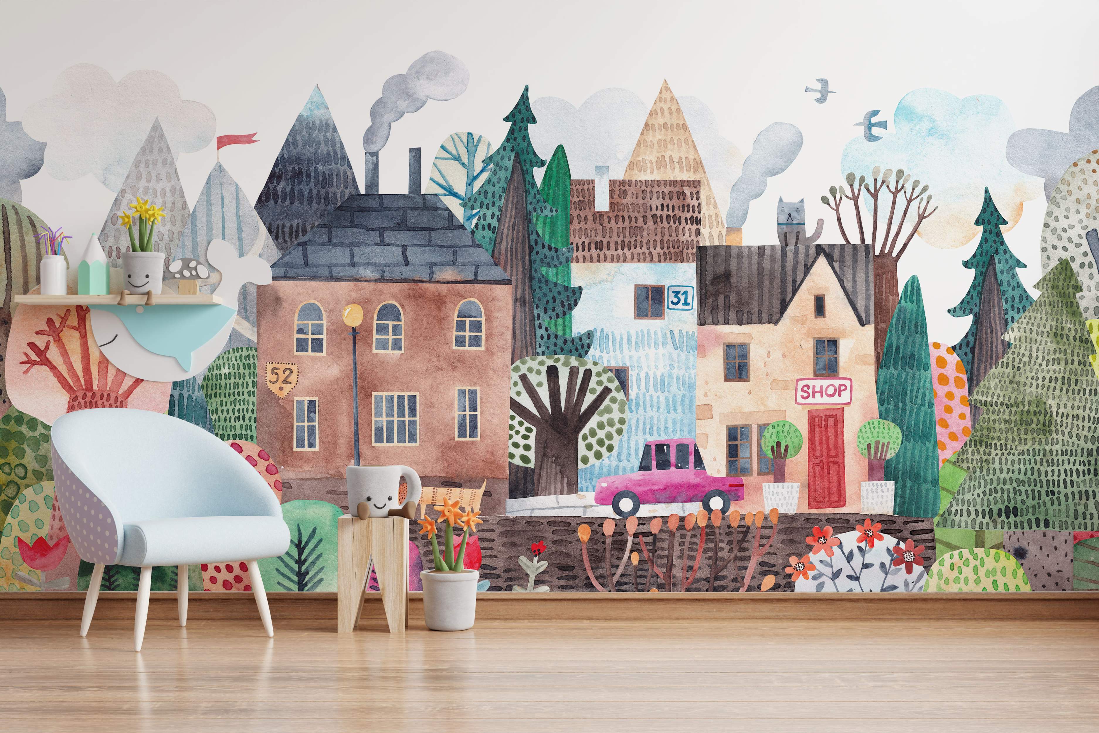 Whimsical watercolor mural depicting a colorful town scene with stylized houses, trees, mountains, and clouds.