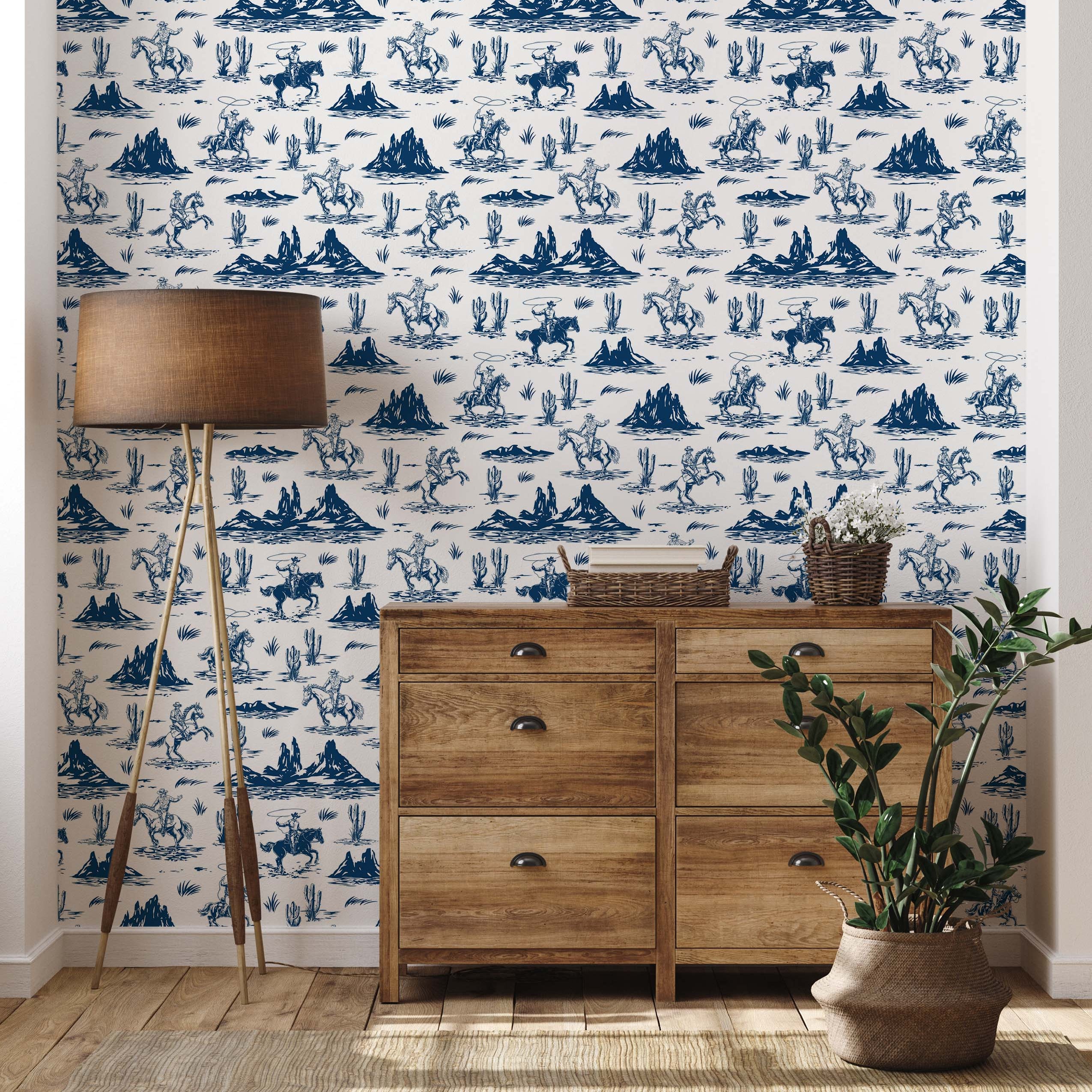 A western toile wallpaper featuring illustrations of cowboys, horses, and cacti in navy blue on a cream background.