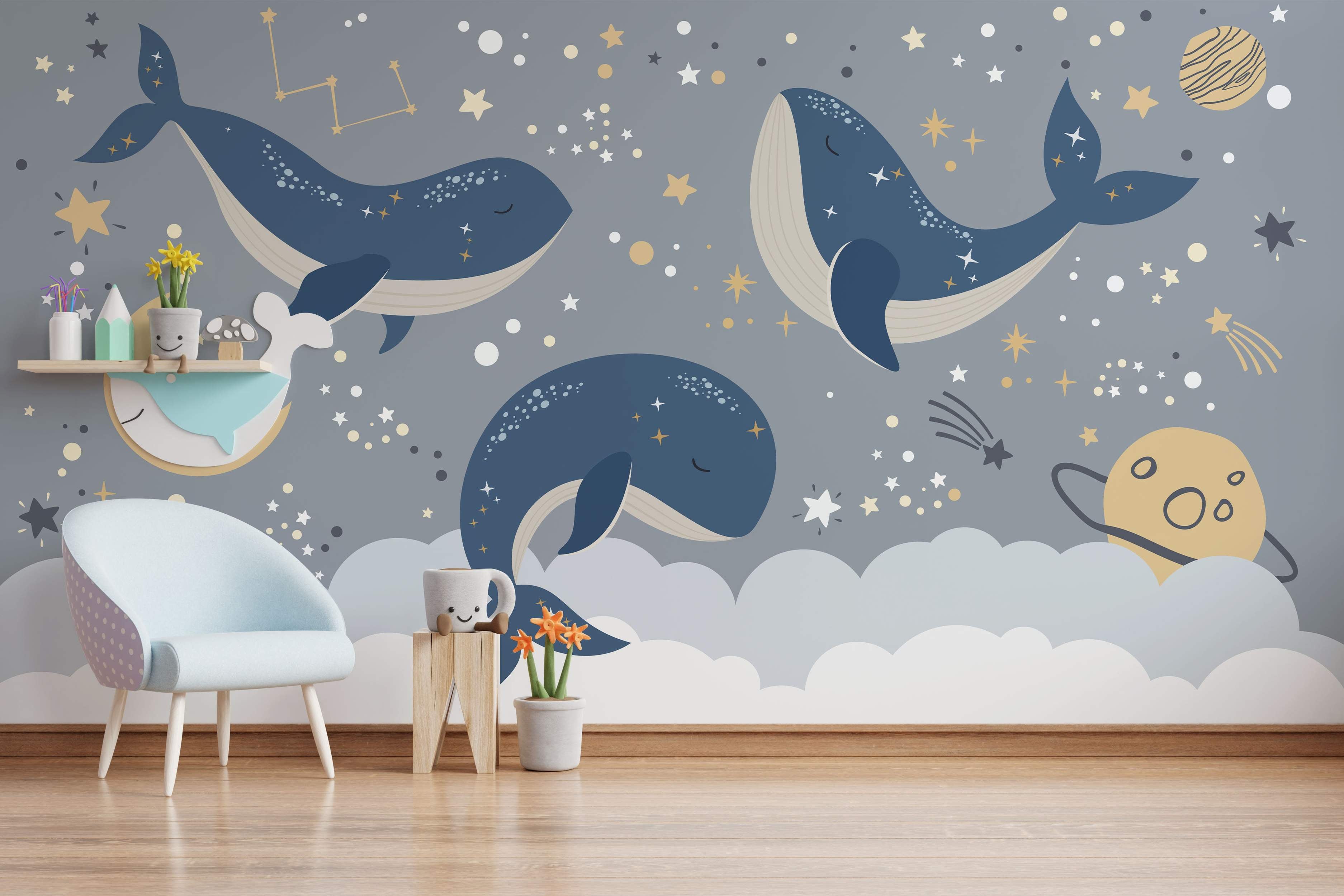 Mural featuring three blue cartoon whales sleeping among stars, constellations, planets, and clouds on a gray background.