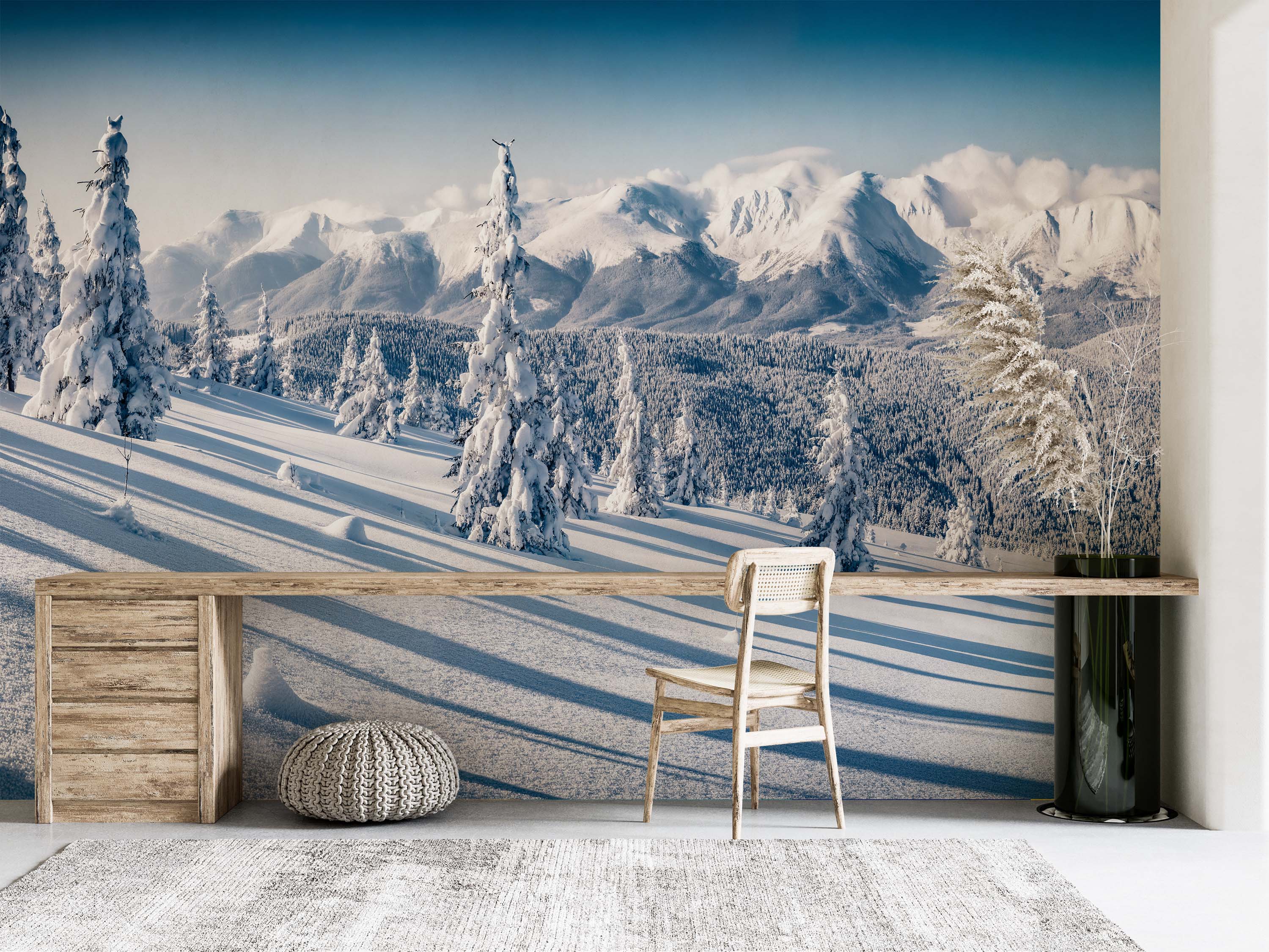 A photorealistic mural of a vast, sunny winter landscape with snow-covered mountains, evergreen trees, and a clear blue sky.