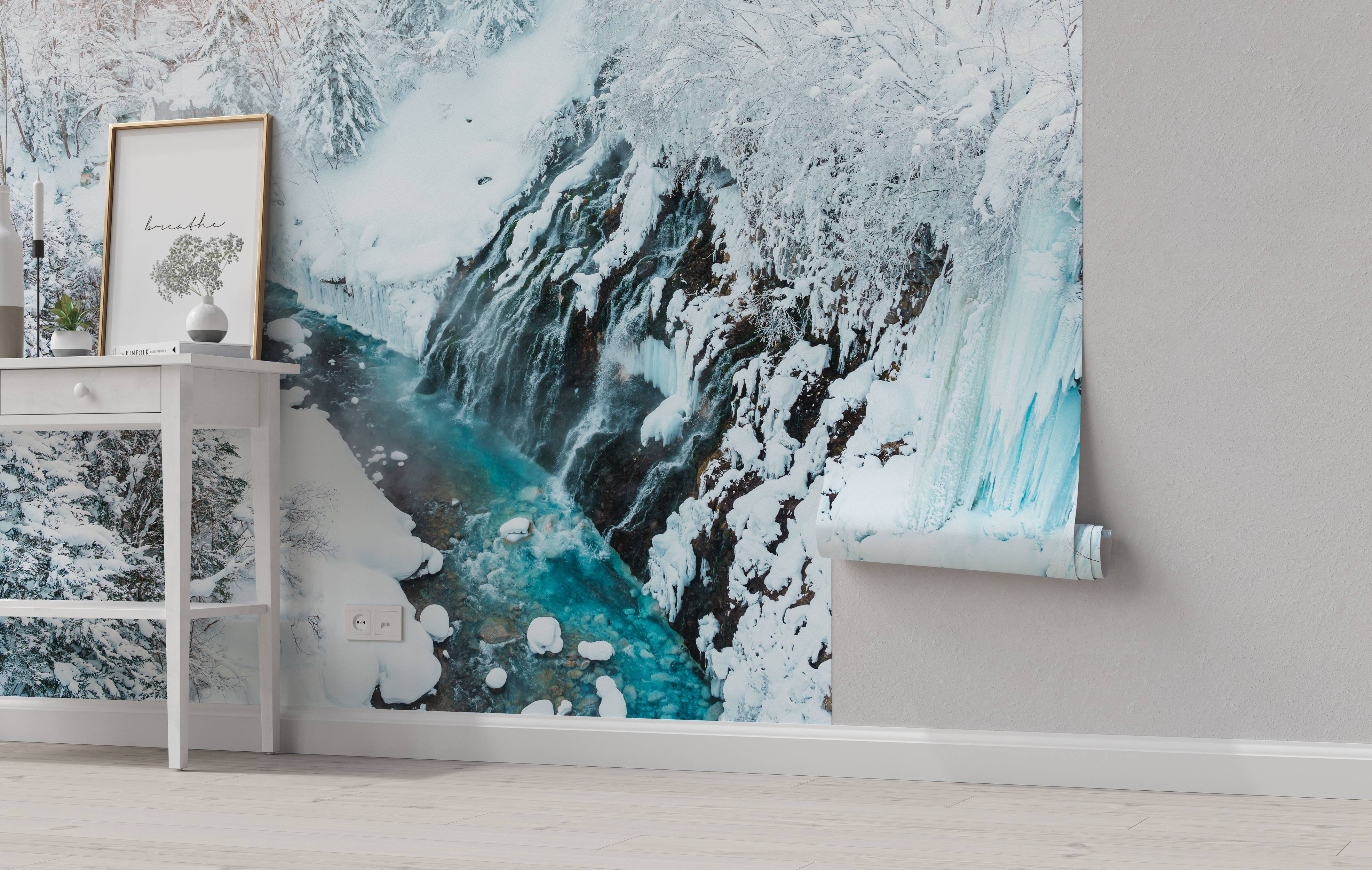 A scenic wall mural of a waterfall in winter. Turquoise water flows down a dark, rocky cliff covered in white snow and icicles.