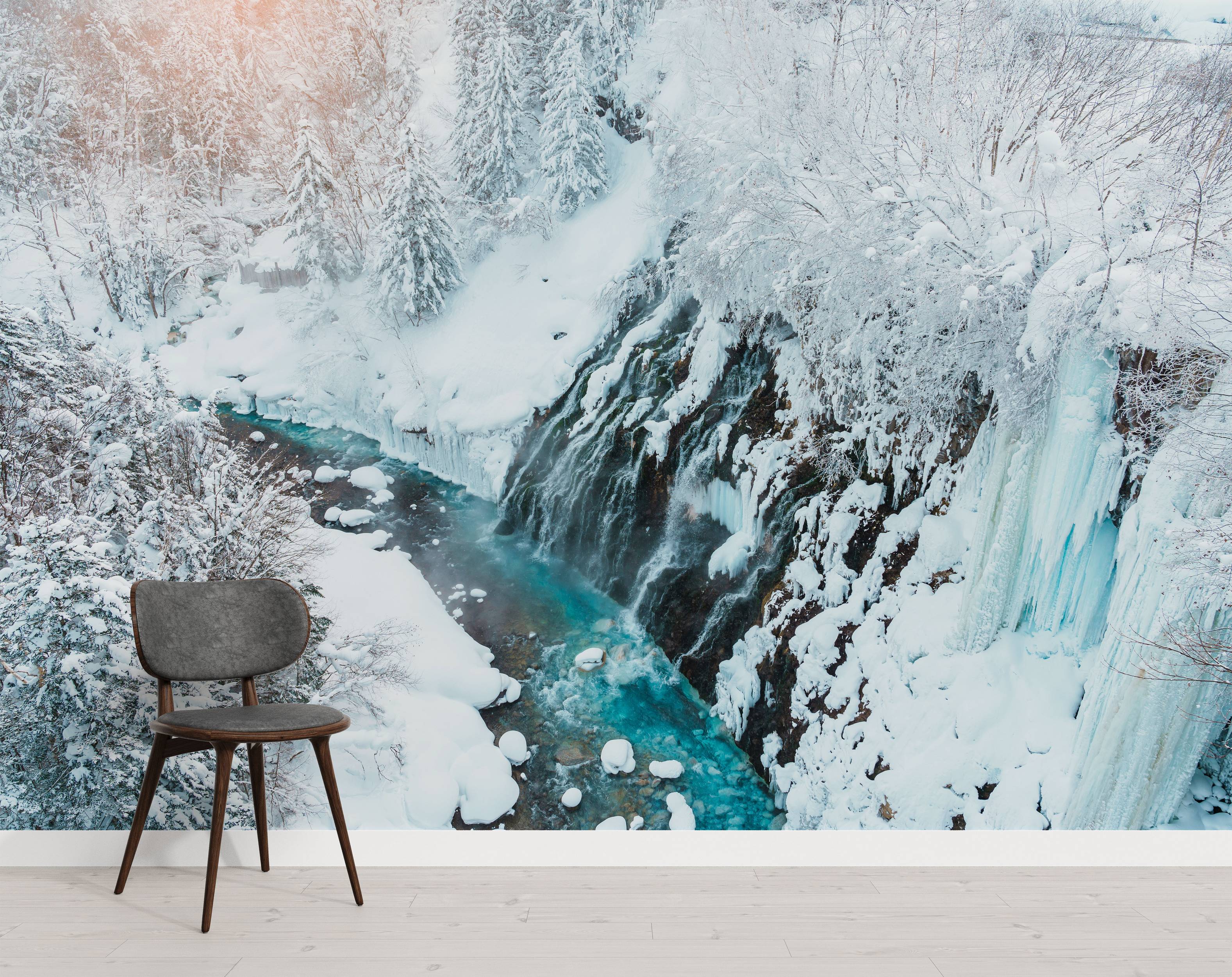 A photorealistic mural of a winter landscape with a partially frozen waterfall and a vibrant turquoise river in a snowy forest.