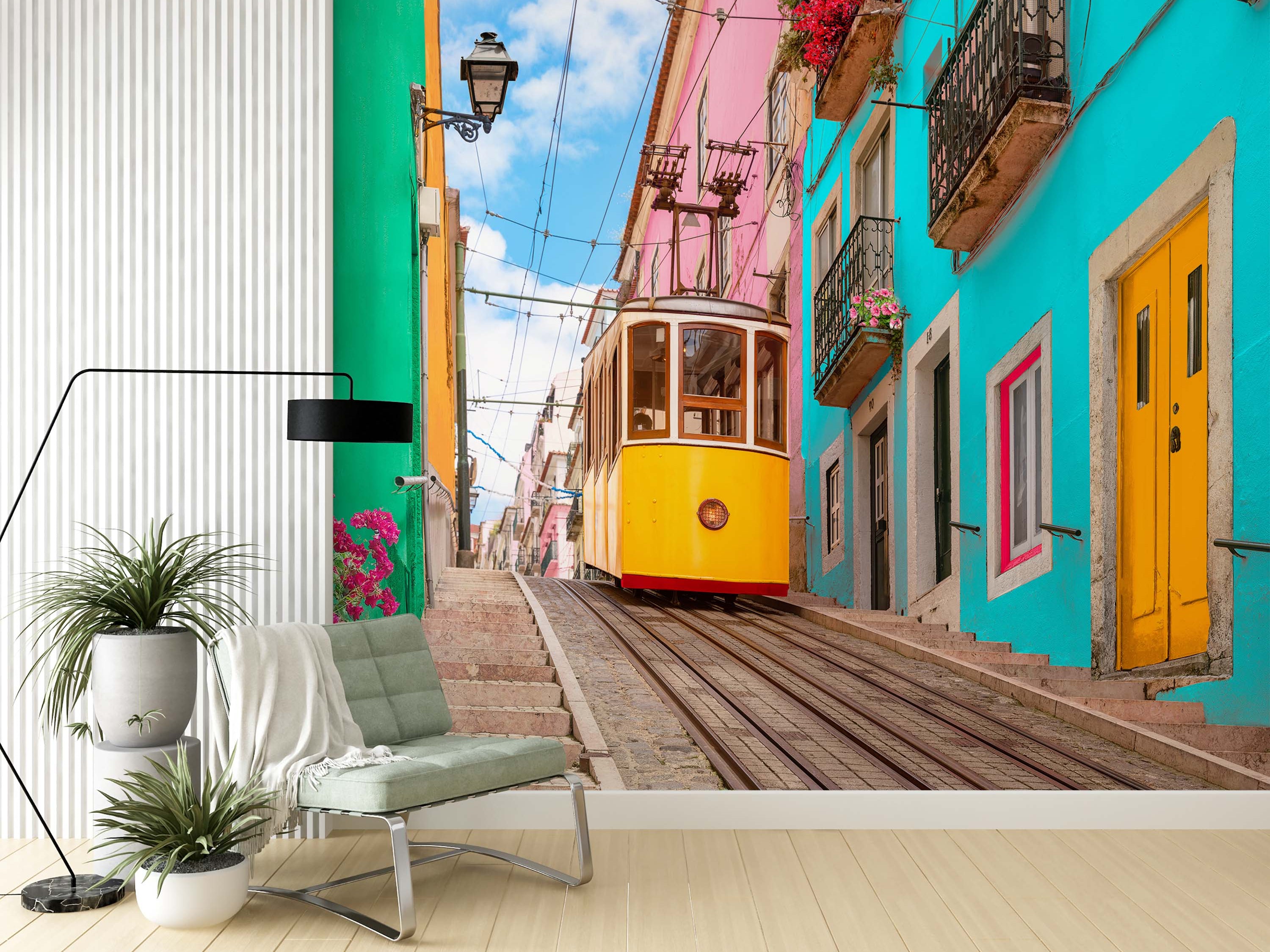 A vibrant city scene mural featuring a yellow tram on a steep cobblestone street, lined with colorful pink and turquoise buildings.